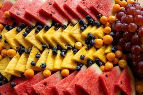 colourful slices of pineapple, watermelon, blueberries, grapes and uchuva fruit presented on a board