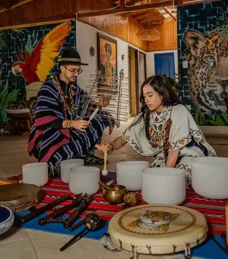 Yageceros Sergio and his wife Vanessa doing a sound healing ceremony, playing crystal sound bowls and the glass harp. other instruments are laid out beautifully on the floor.