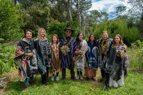 the whole team standing smiling in nature from Harmonica Ayahuasca Retreat, in Medellín Colombia