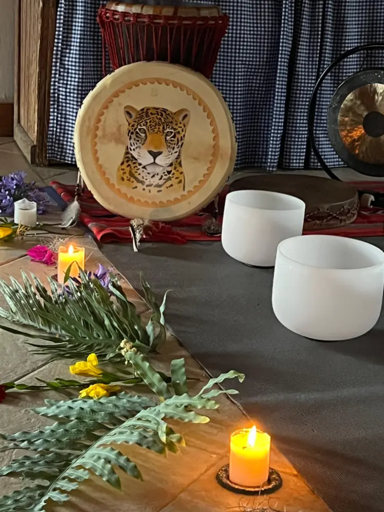 A jaguar frame drum, gong, singing bowls, flowers and candles set out on the floor before a breathwork session at Harmonica Retreat