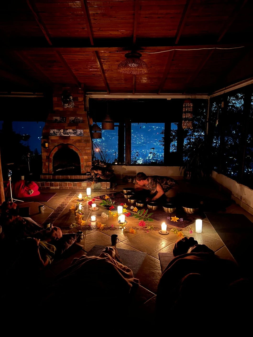 Participants resting by candlelight at an evening sound healing ceremony above the lights of Medellin