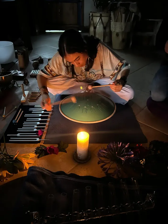 A facilitator playing a handpan during sound healing by candlelight