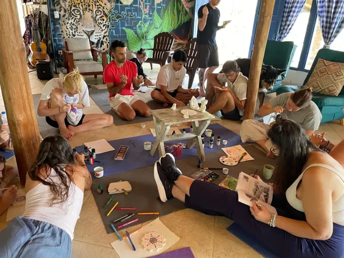 Participants painting and drawing together on the floor during an art session