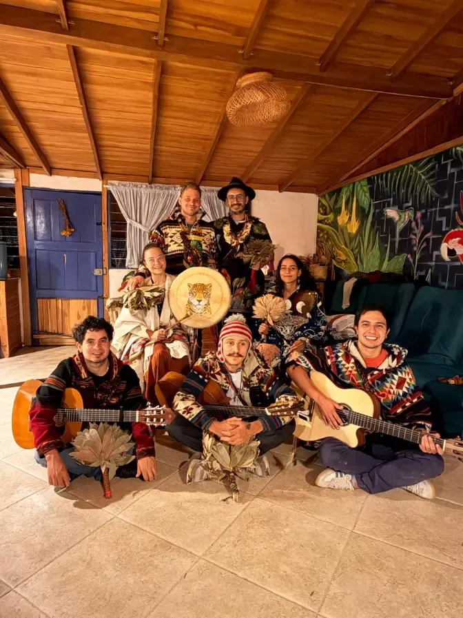The group sitting together with guitars and a painted drum