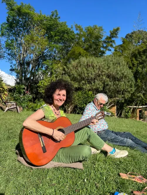 A participant playing guitar on the grass in the sunshine