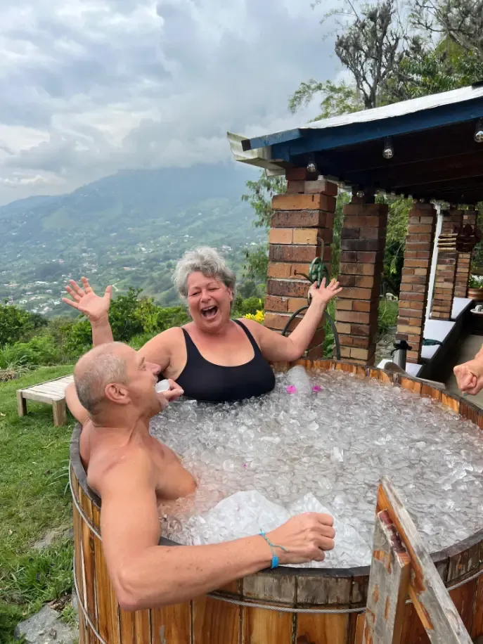 Two participants laughing in the ice bath with the mountains behind
