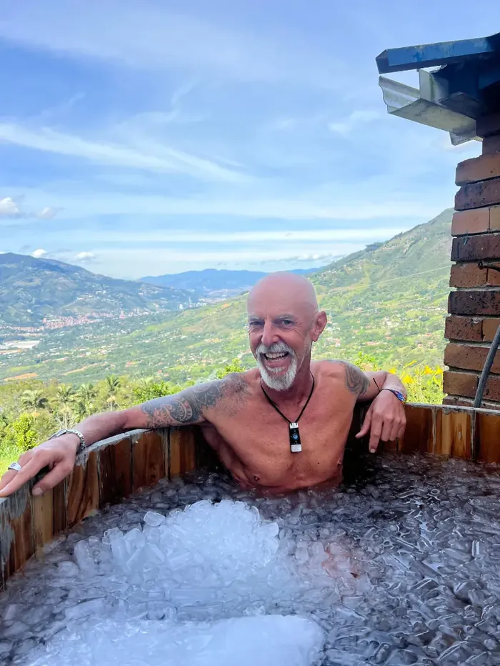 A participant smiling in the ice bath with a view of the valley