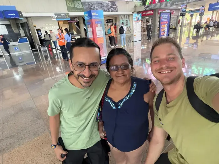 Three people smiling together for a selfie at the airport