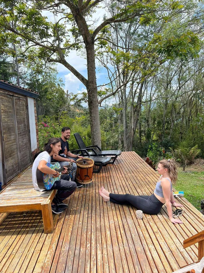 Participants playing guitar and stretching on the wooden deck among tall trees