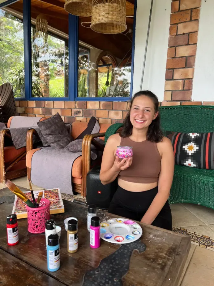 A participant smiling with a painted object on the porch