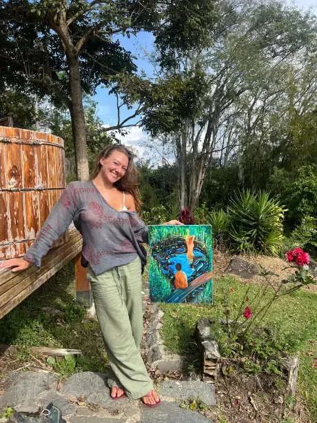 A participant showing her finished painting in the garden
