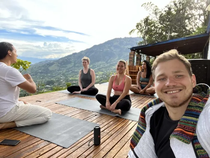 Participants doing yoga on the wooden deck with the mountains behind