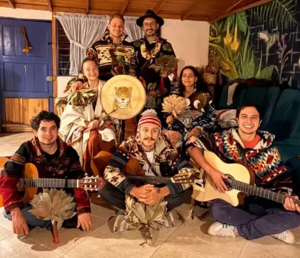 The Harmonica Retreat team sitting together with guitars, a drum and feather fans